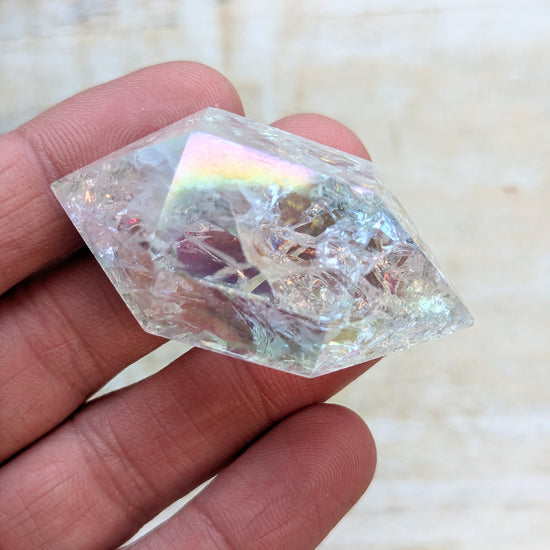 Angel Aura Quartz Wand Double Terminated held in a hand against a neutral background