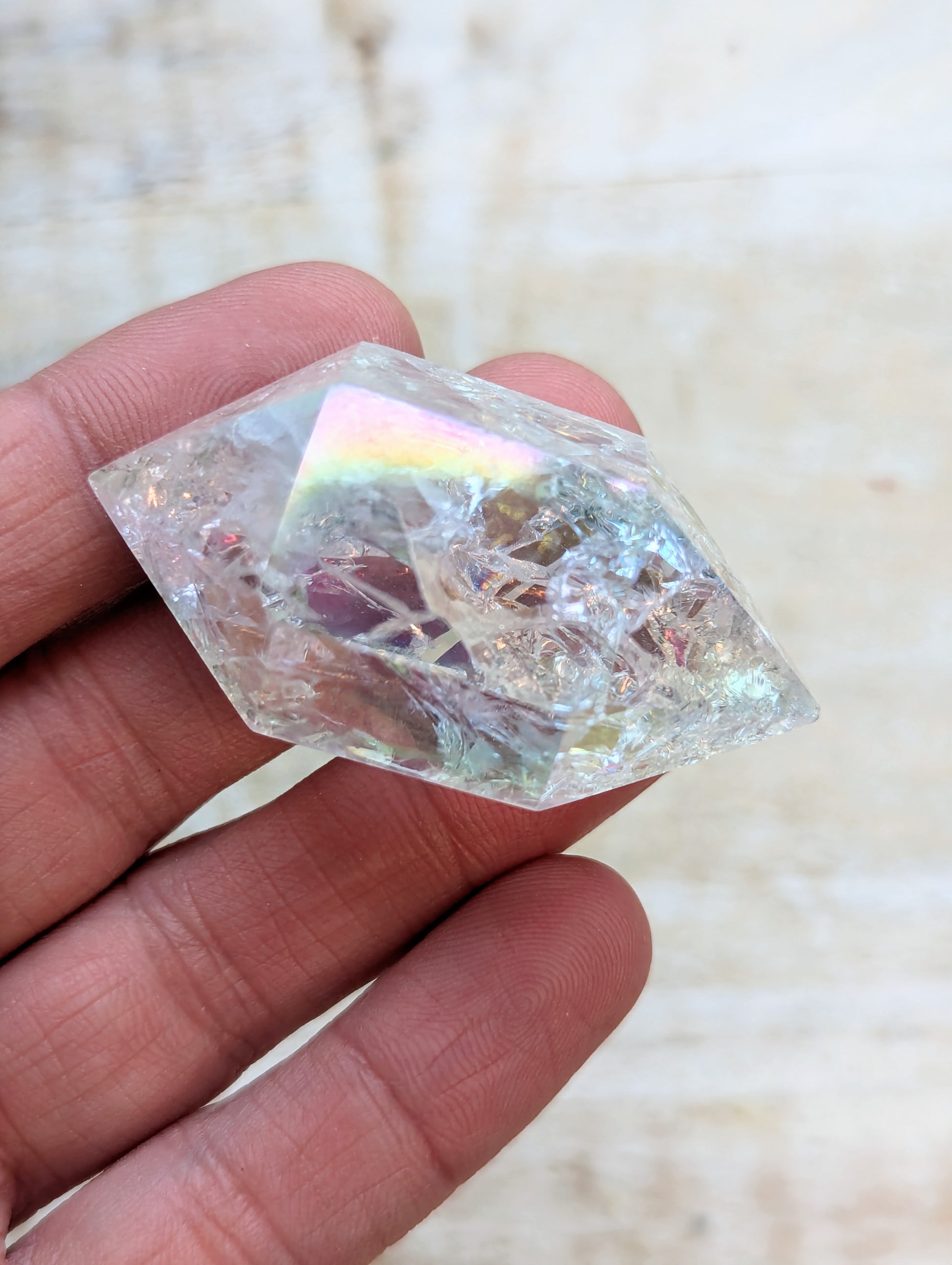 Angel Aura Quartz Wand Double Terminated held in a hand against a neutral background
