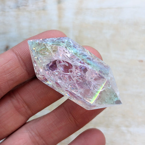 Angel Aura Quartz Wand Double Point held in a hand with a blurred background