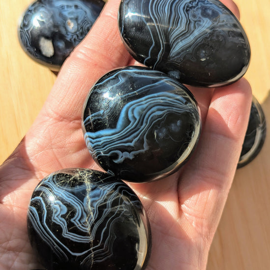 Black onyx stones held in a hand on a wooden surface