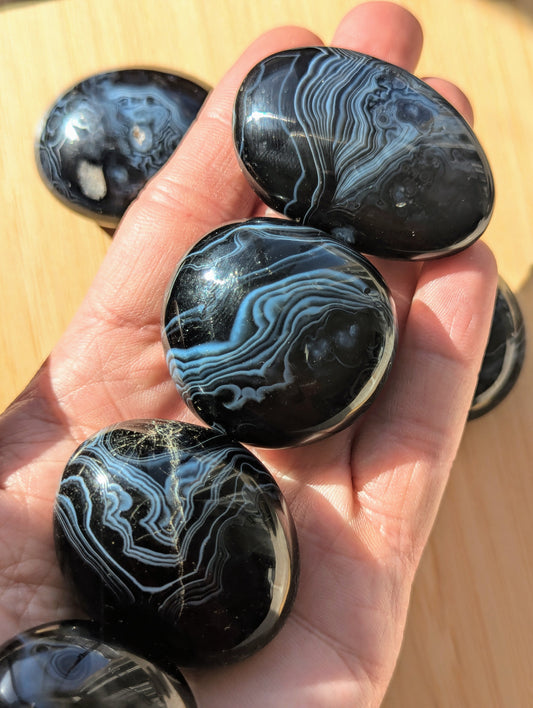 Black onyx stones held in a hand on a wooden surface