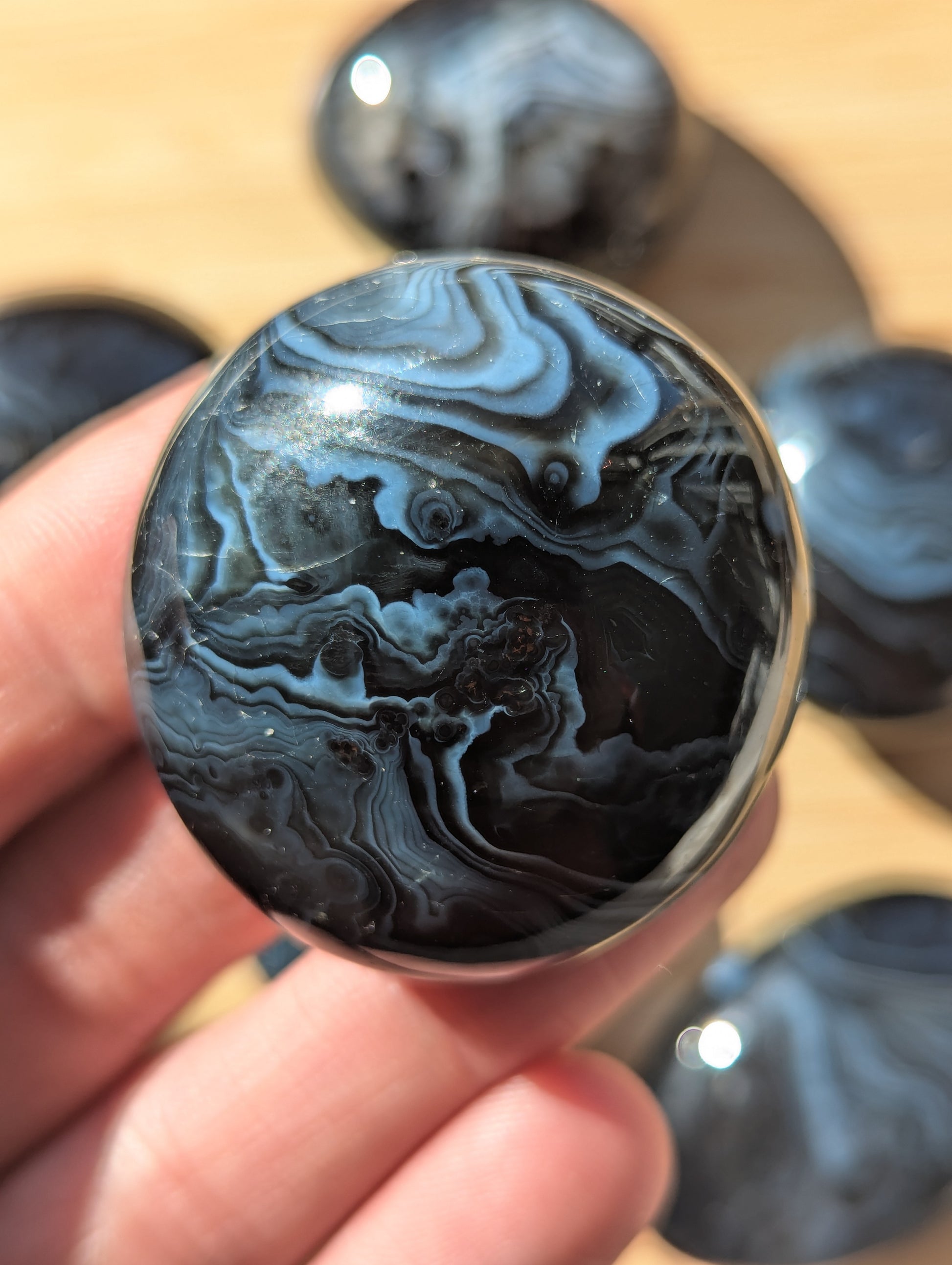 Close-up of a black onyxstone held in a hand with more stones in the background.