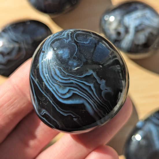 Black onyx stone held in a hand with more stones in the background