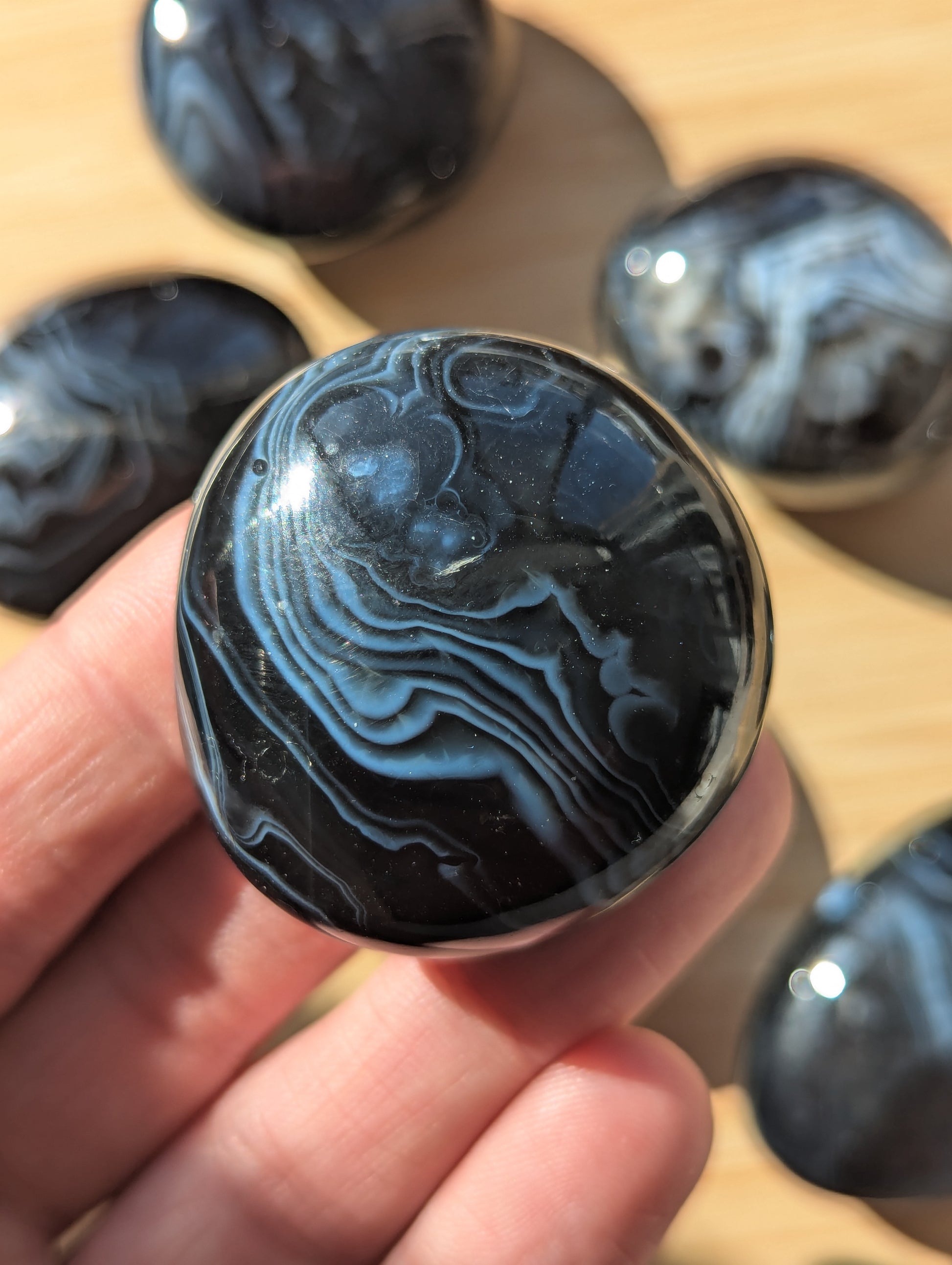 Black onyx stone held in a hand with more stones in the background