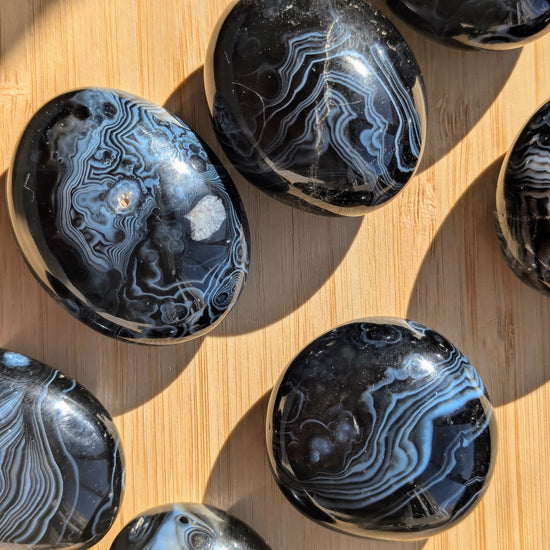 Polished black onyx tumbled stones on a wooden surface