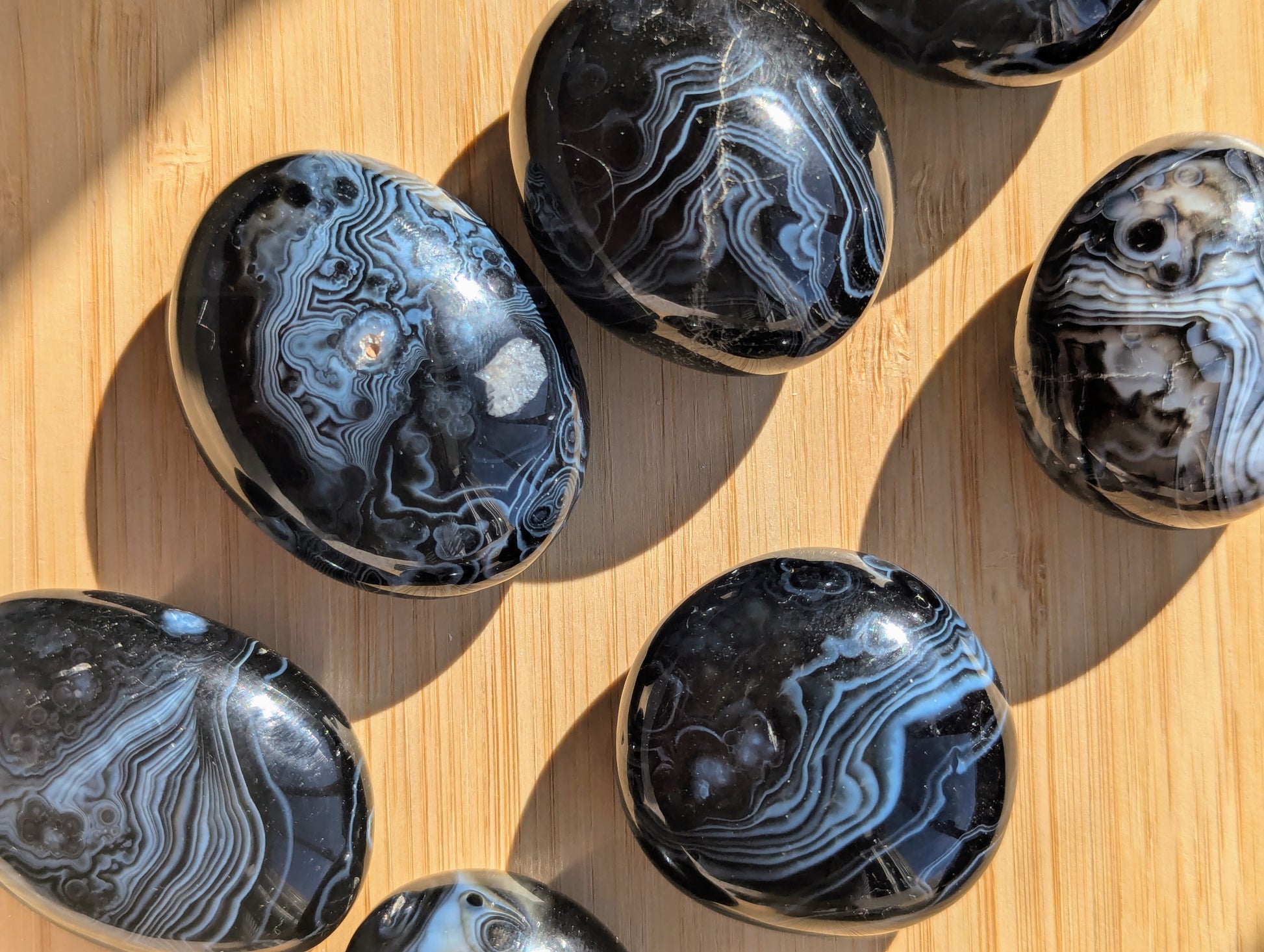 Polished black onyx tumbled stones on a wooden surface
