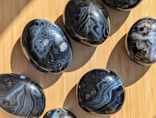 Polished black onyx tumbled stones on a wooden surface