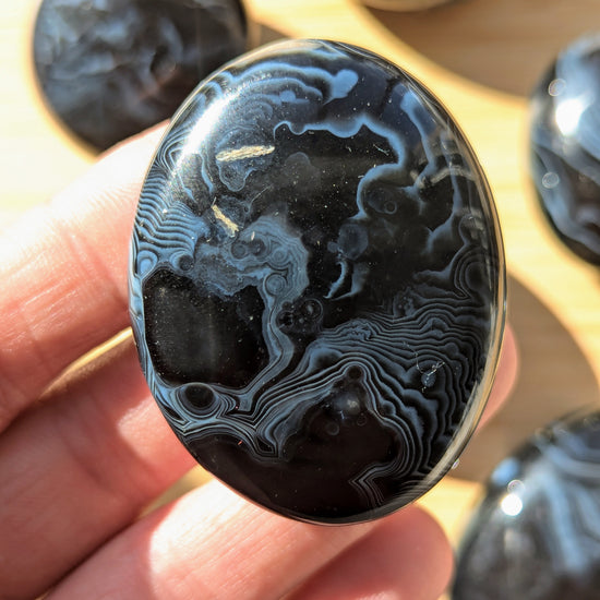 Black onyx crystal stone held in a hand with more stones in the background