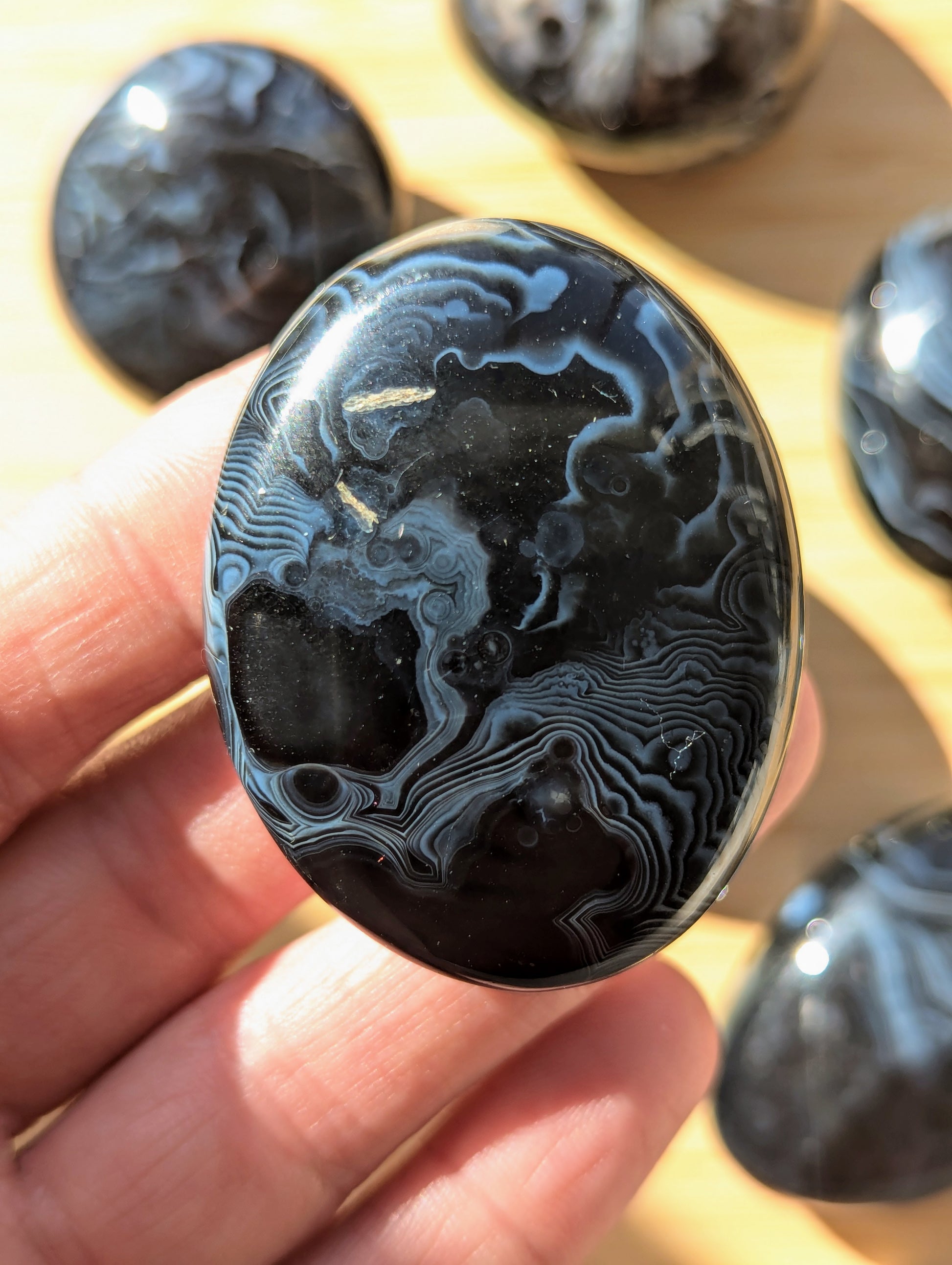 Black onyx crystal stone held in a hand with more stones in the background