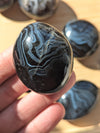 Black onyx stone held in a hand with more stones in the background.
