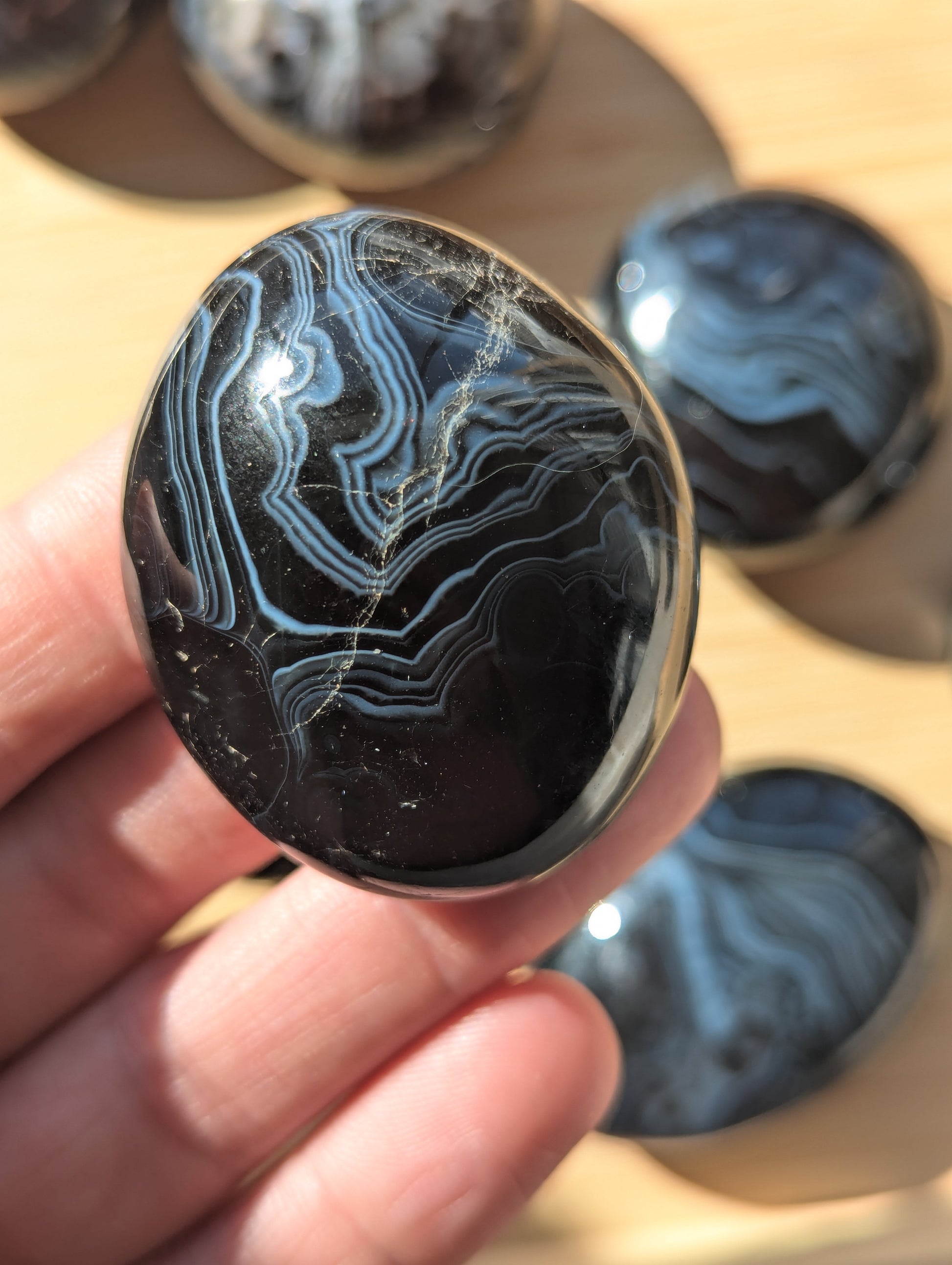 Black onyx stone held in a hand with more stones in the background.