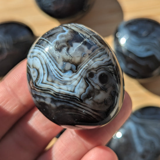 Close-up of a black onyx stone held in a hand with a blurred background