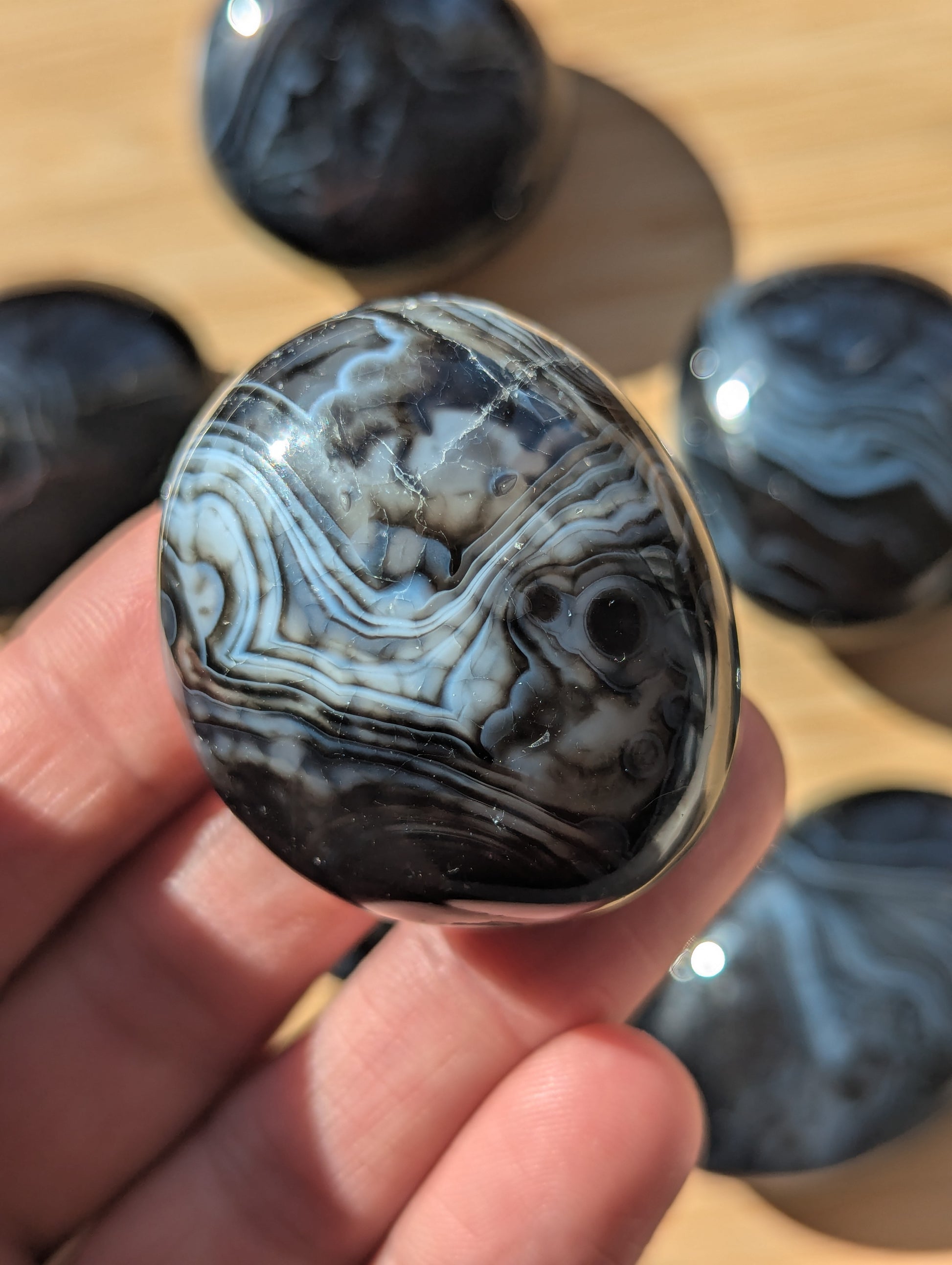 Close-up of a black onyx stone held in a hand with a blurred background