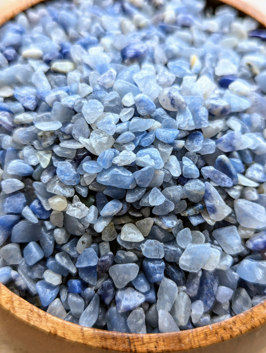 Close-up of blue aventurine crystal chips in a wooden bowl