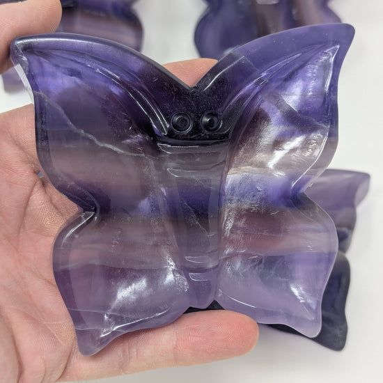 Purple butterfly-shaped gel pack held in a hand against a white background