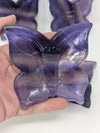 Purple butterfly-shaped gel pack held in a hand against a white background