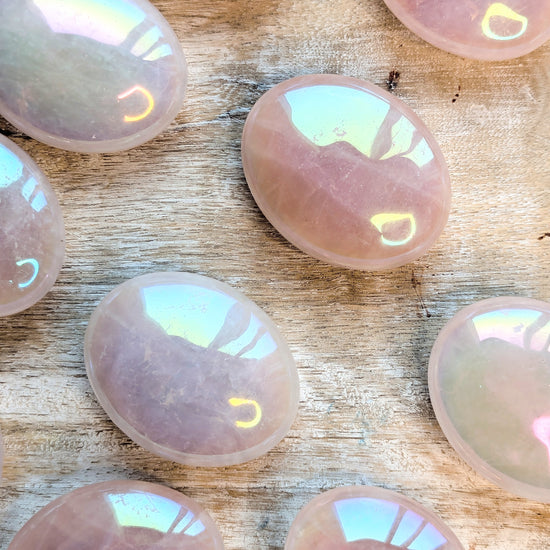 Iridescent Angel Aura Rose Quartz Palm Stones stones on a wooden surface