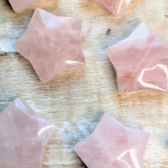 Rose quartz star carving pieces on a wooden surface