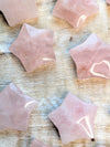 Rose quartz star carving pieces on a wooden surface