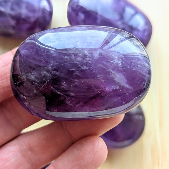 Purple gemstone held in a hand with a blurred background