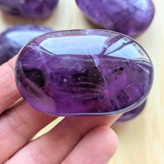 Close-up of a purple crystal held in a hand with more crystals in the background.