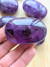 Close-up of a purple crystal held in a hand with more crystals in the background.