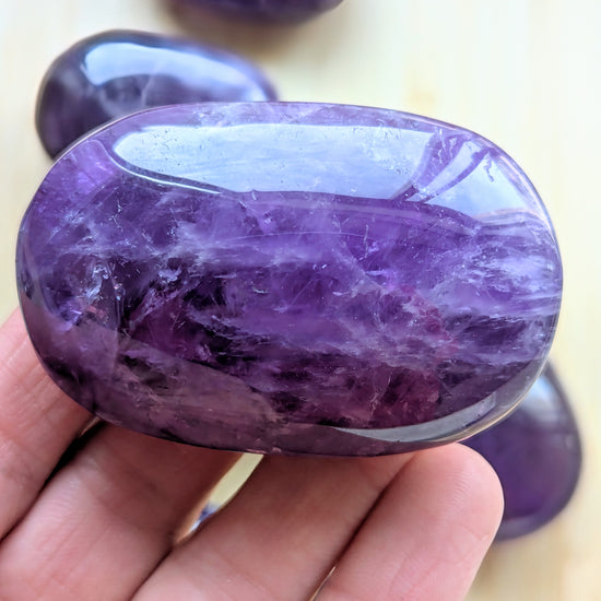 Purple amethyst stone held in a hand with a blurred background