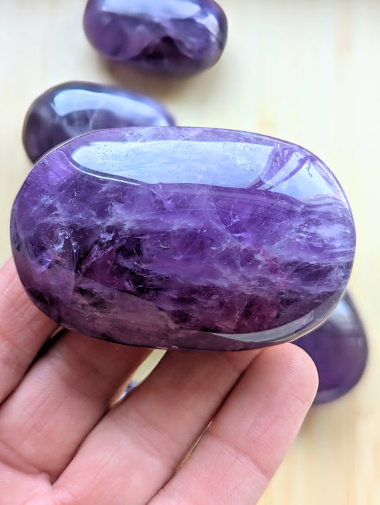 Purple amethyst stone held in a hand with a blurred background