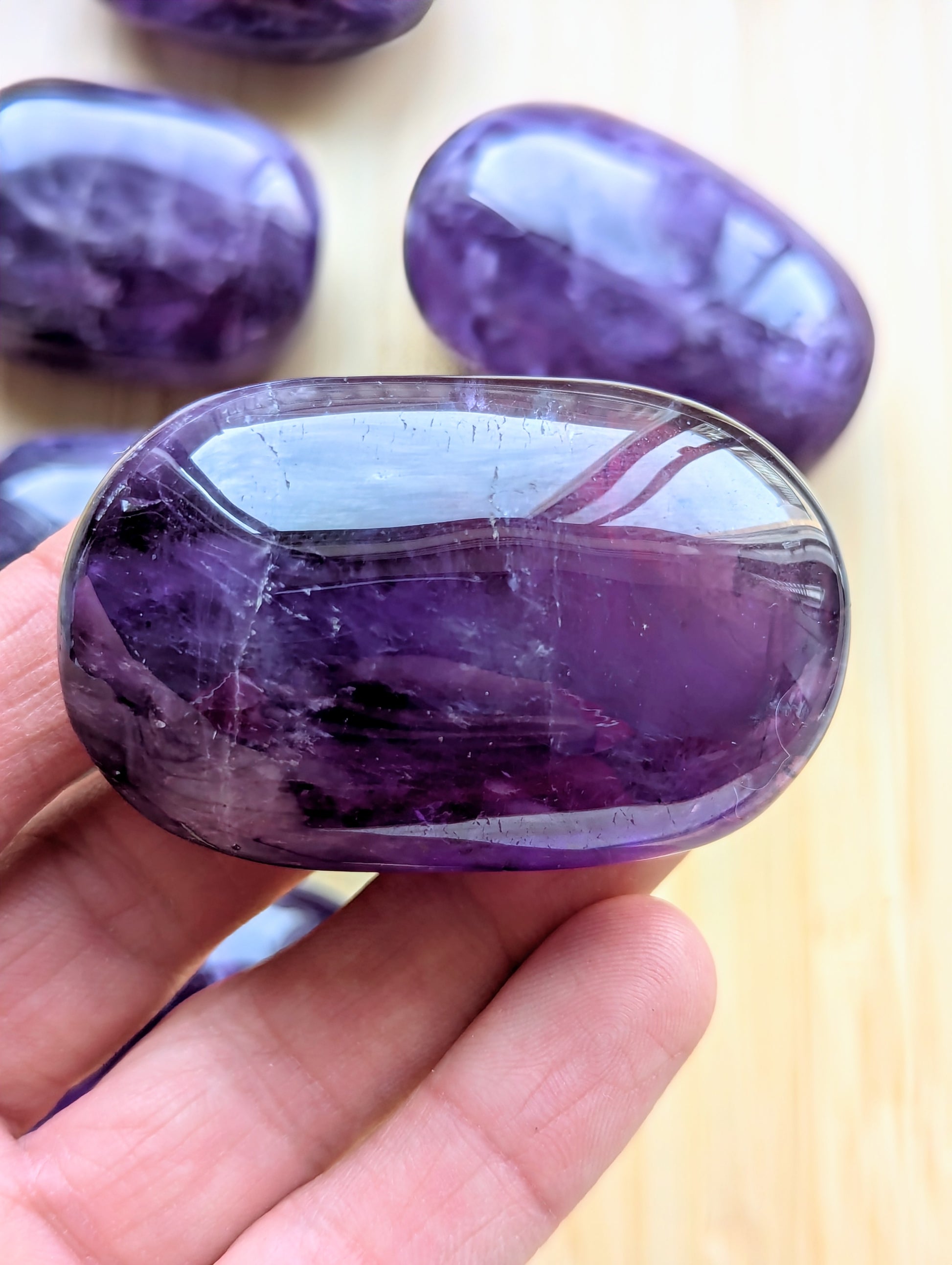 Purple gemstone held in a hand with more gemstones in the background