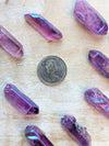 Angel Aura Purple crystal-like objects on a wooden surface with a coin for scale.