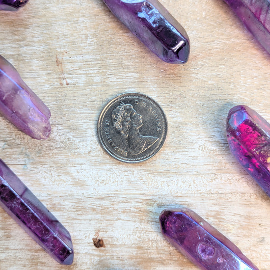 Angel Aura Purple crystal on a wooden surface with a coin for scale.