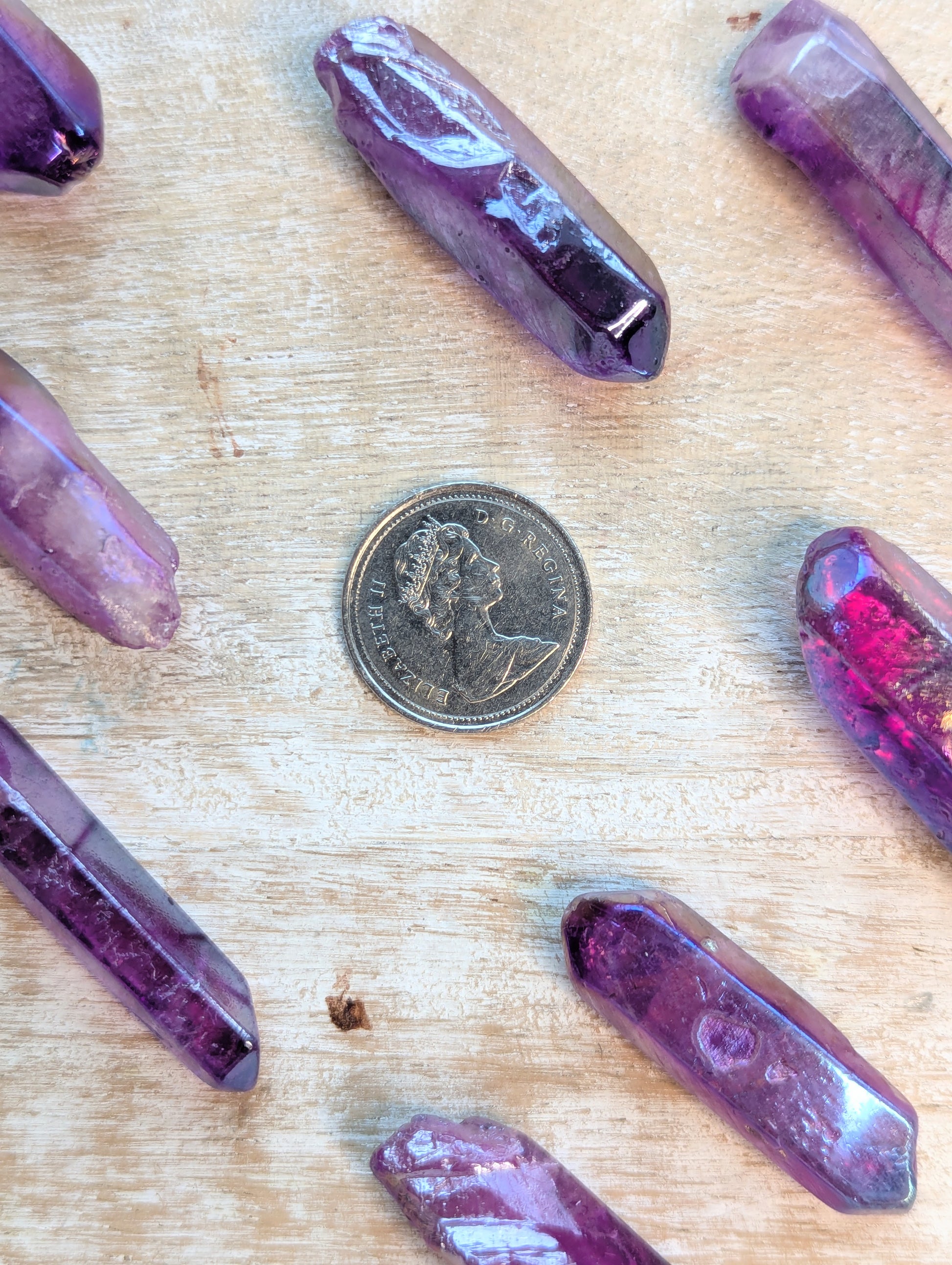 Angel Aura Purple crystal on a wooden surface with a coin for scale.