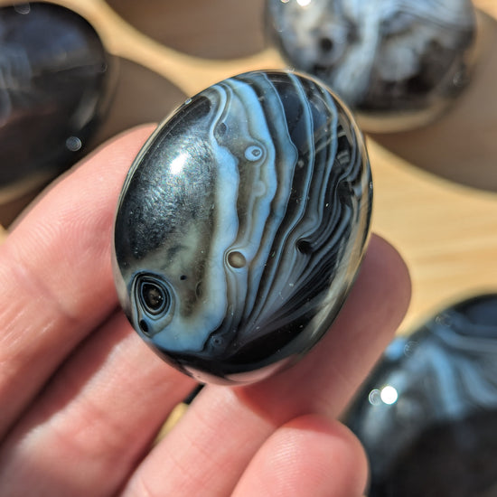 Black onyx stone held in a hand with more stones in the background