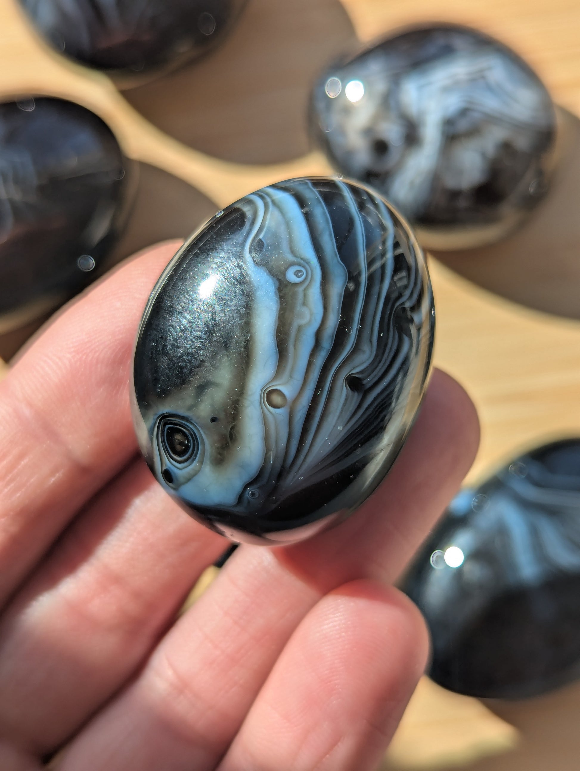 Black onyx stone held in a hand with more stones in the background