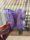 Purple butterfly-shaped object held in a hand with a blurred background