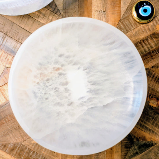 A round white stone bowl with a cloudy, marbled texture, photographed from above on a rustic wooden surface.