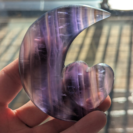 Hand holding a purple crystal with a blurred background