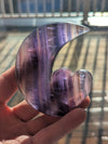 Hand holding a purple crystal with a blurred background