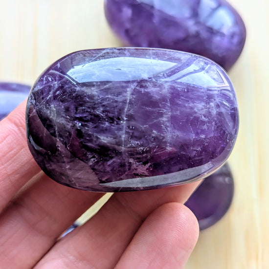 Purple stone held in a hand with a blurred background