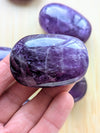 Purple stone held in a hand with a blurred background