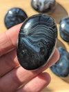 Black onyx stone held in a hand with more stones in the background