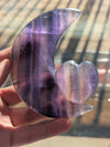 Hand holding a purple crystal heart-shaped object with a blurred background