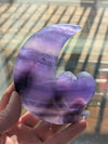 Hand holding a purple and clear crystal with a blurred background