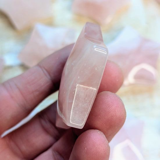 Rose quartz star carving on a finger against a blurred background