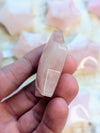 Rose quartz star carving on a finger against a blurred background