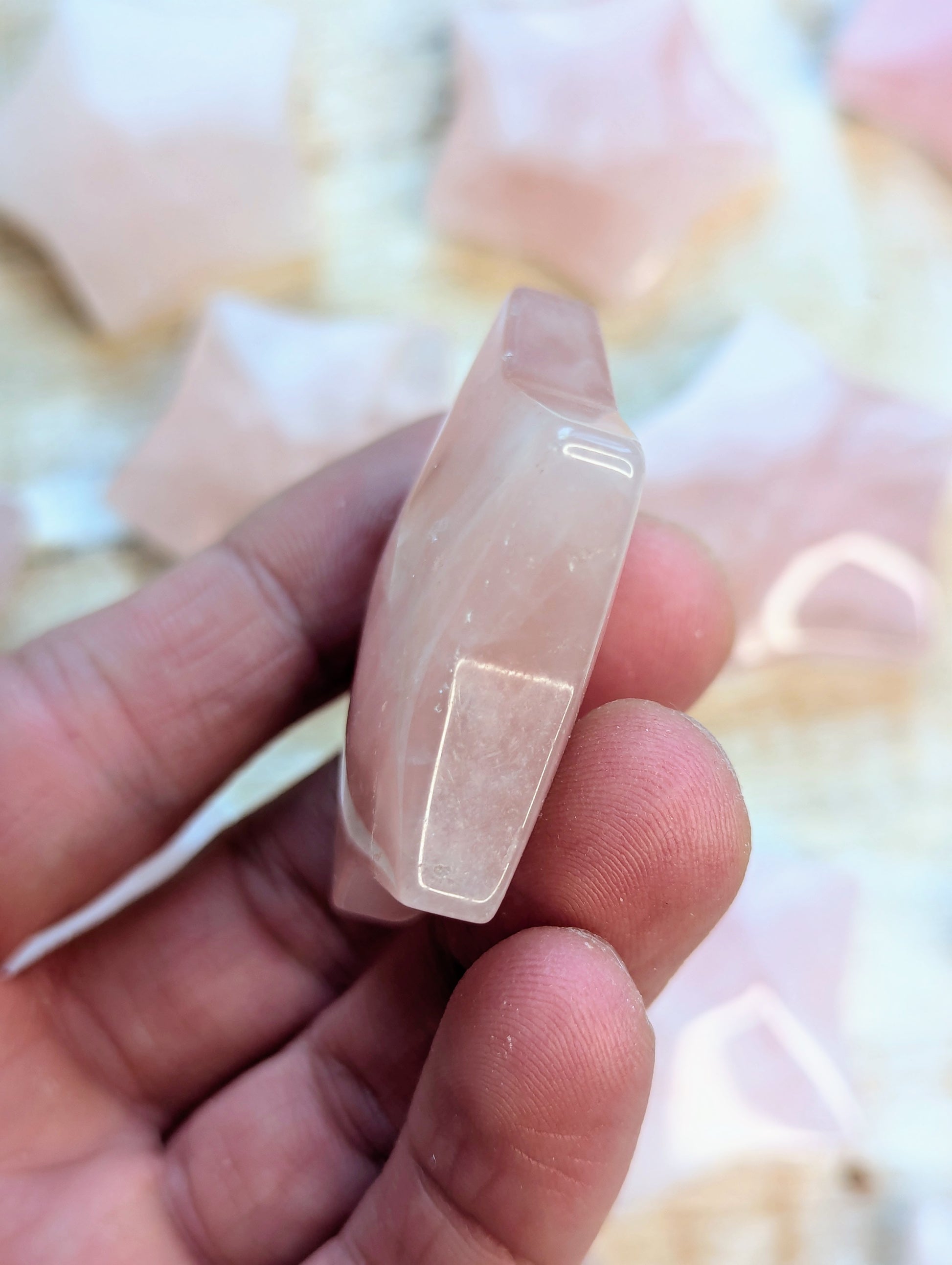 Rose quartz star carving on a finger against a blurred background