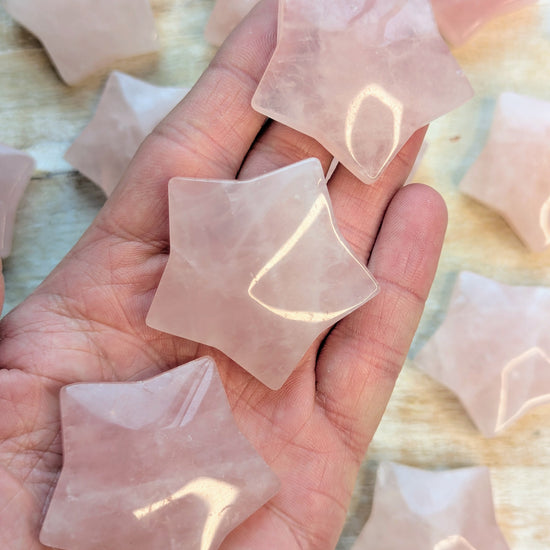 Hand holding star-shaped rose quartz crystals with a blurred background