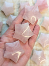 Hand holding star-shaped rose quartz crystals with a blurred background