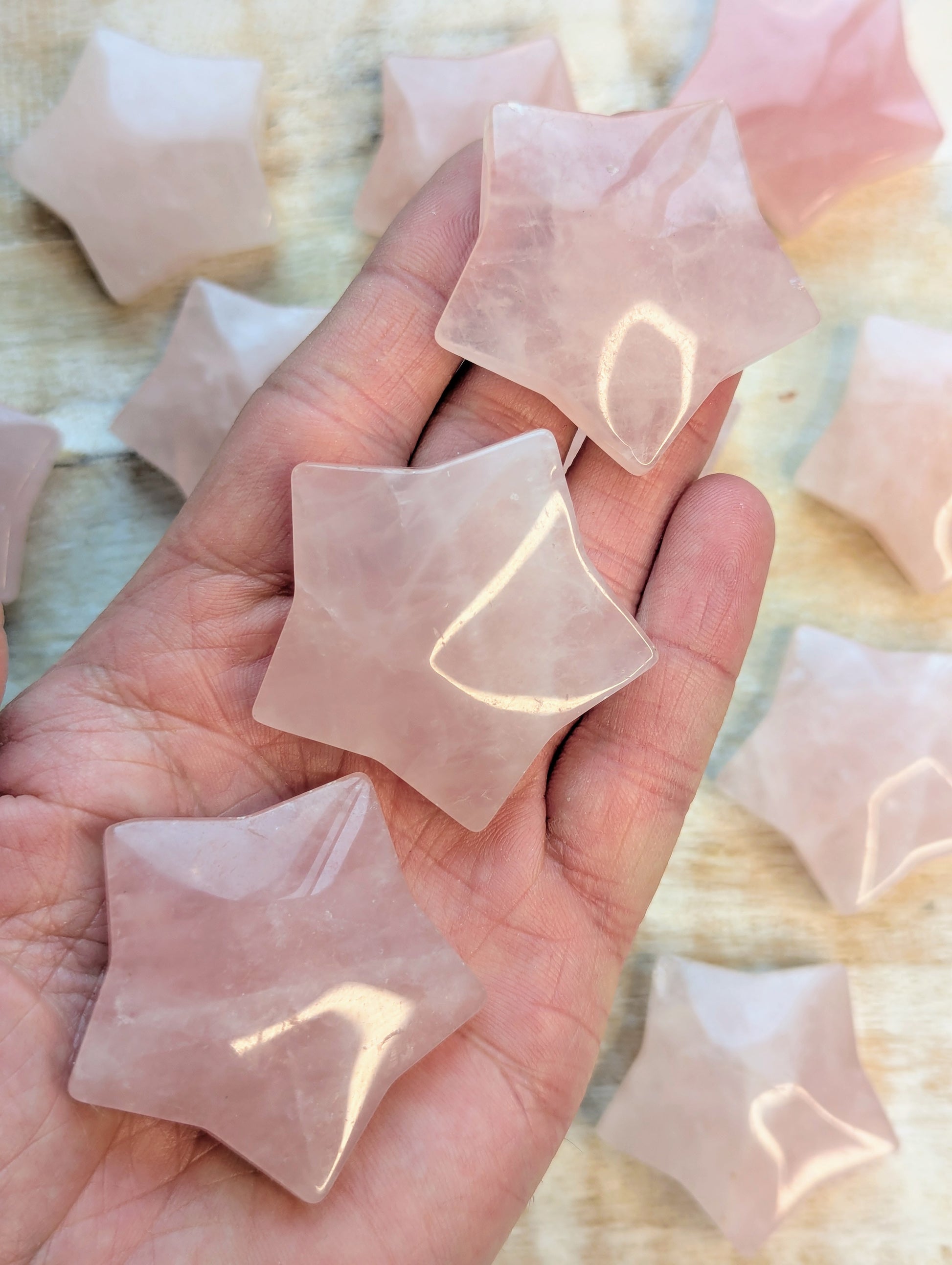 Hand holding star-shaped rose quartz crystals with a blurred background